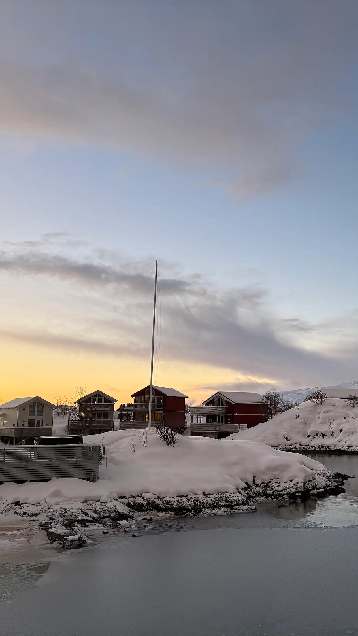 Casas de pescadores em Sommarøy, com neve e mar calmo.