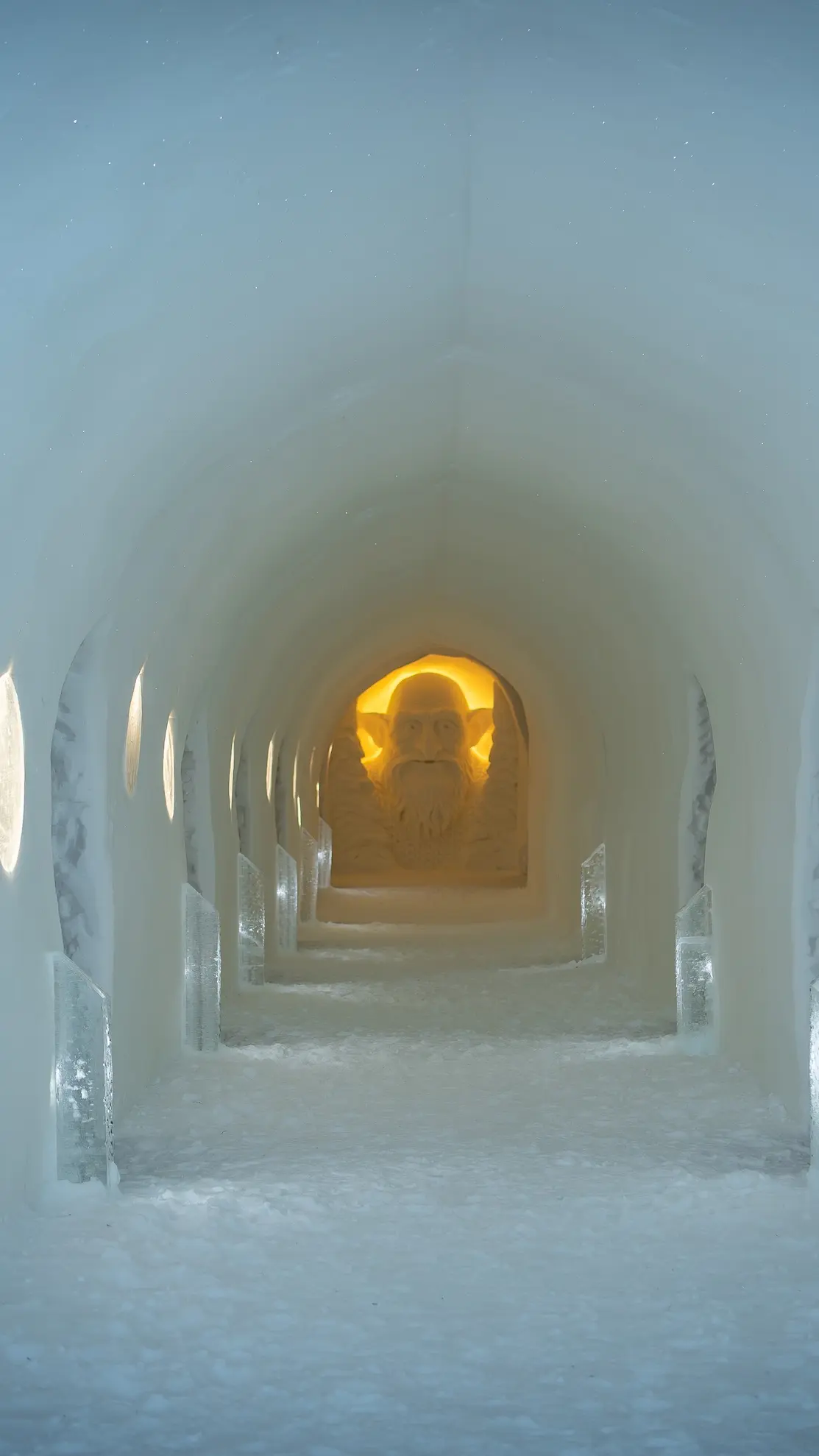 Corredor de gelo do Igloo Hotel, com uma luz âmbar no fim.