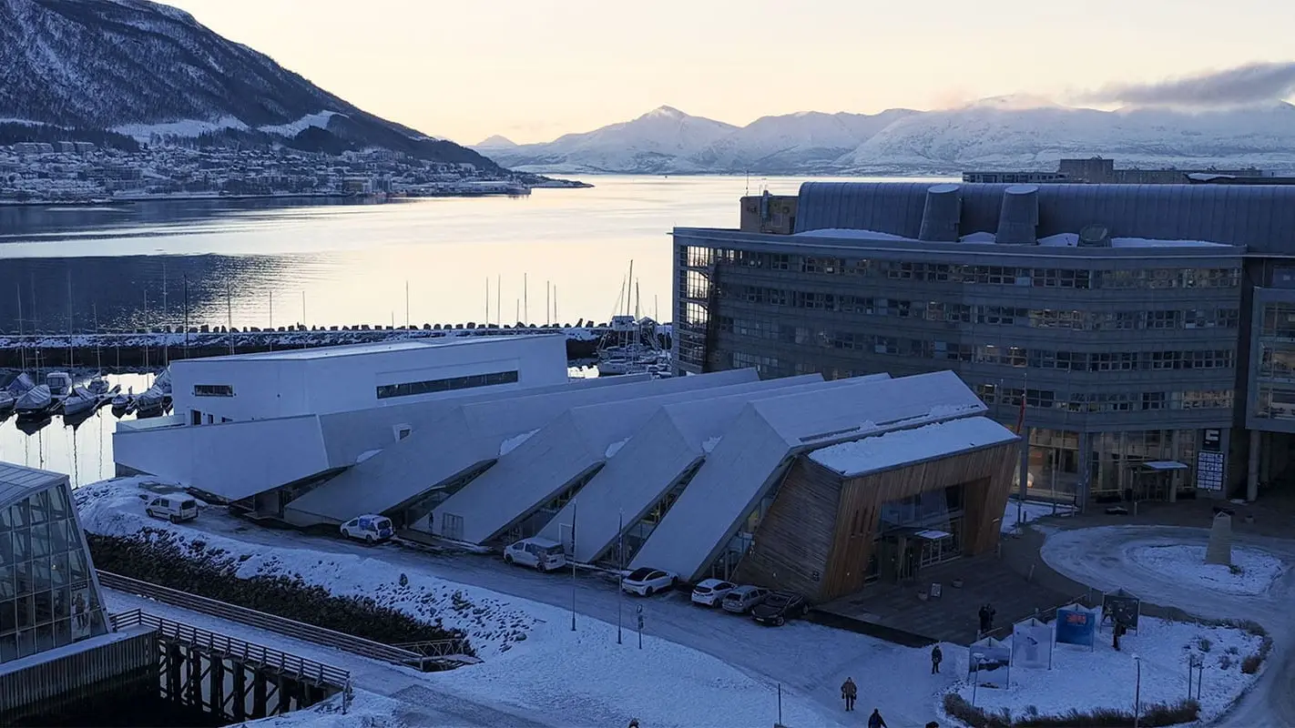 O prédio da Polaria no inverno, em placas inclinadas como gelo, na beira do porto de Tromsø.